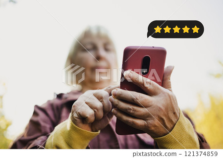 Customer Experience Concept. Excellent. Happy senior woman pressing face emoticon on virtual touch screen at smartphone .Customer service evaluation concept. Customer Experience Concept. Excellent. Happy senior woman pressing face emoticon on virtual touch screen at smartphone .Customer service evaluation concept. 121374859