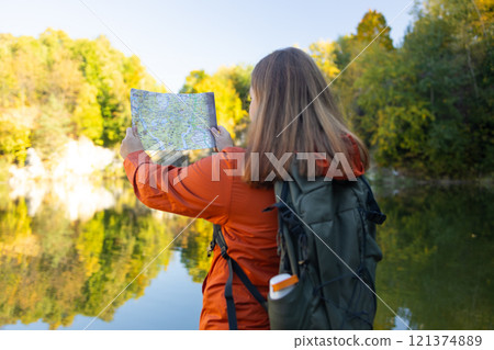 Traveling Happy Caucasian woman with backpack walking on path the mountain forest looking at the camera and map. Summer holiday and vacation trip Traveling Happy Caucasian woman with backpack walking on path the mountain forest looking at the camera and map. Summer holiday and vacation trip 121374889
