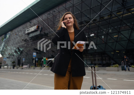 Smiling female business professional hailing taxi. Happy businesswoman waiting for taxi on the city street. 121374911