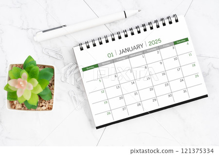 Desk calendar on month of January 2025 with pen on white marble background. Desk calendar on month of January 2025 with pen on white marble background. 121375334