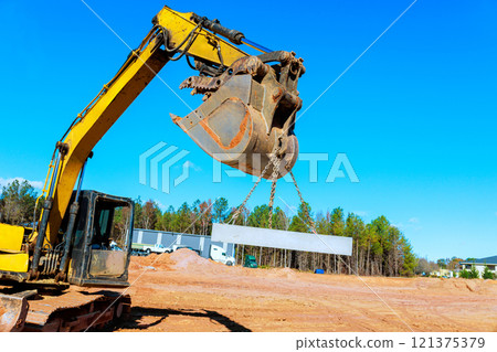 Construction workers operate crane to lift large steel beam at building site during works area 121375379