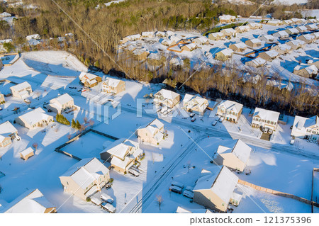 Winter American suburbs aerial view reveals suburban areas covered in snow, highlighting houses, streets, transformed into snowy landscape. 121375396