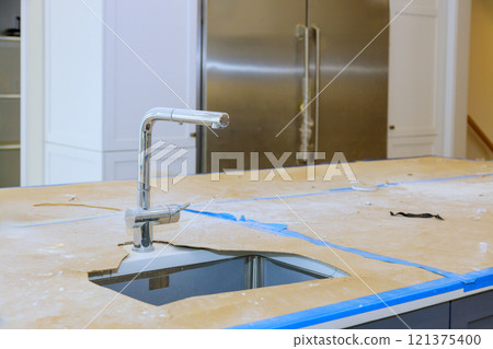 Kitchen under renovation features complete countertop with cutout for sink visible construction materials modern home setting 121375400
