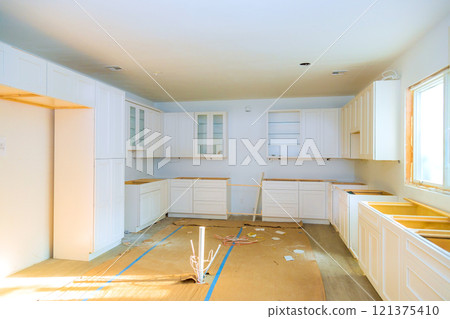 Renovation work in modern kitchen with empty cabinets construction materials scattered during kitchen installation 121375410
