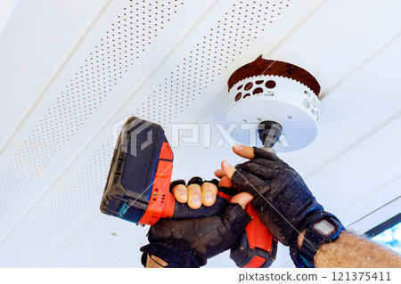 Process of creating clean, precise opening in ceiling with using cordless drill specialized tool to new soffit light Process of creating clean, precise opening in ceiling with using cordless drill specialized tool to new soffit light 121375411