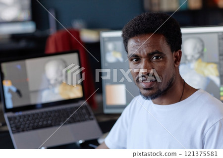 Portrait of African American man standing near computer screen in office environment managing digital work and projects showcasing his professional dedication and workplace surroundings 121375581