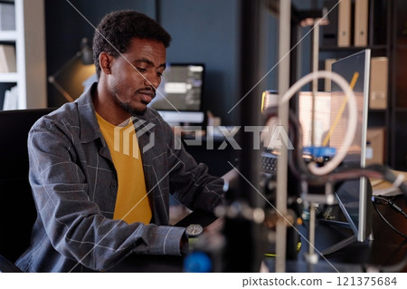Engineer concentrating on writing code at workstation with computer and modern equipment in office setting 121375684