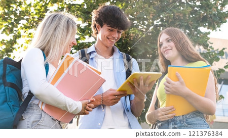Happy young university students using digital tablet on sunny day Happy young university students using digital tablet on sunny day 121376384