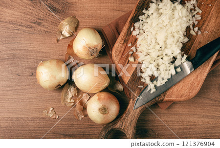 finely chopped onion on a chopping board with a knife, wooden table, top view, no people, finely chopped onion on a chopping board with a knife, wooden table, top view, no people, 121376904