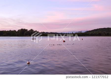 Sunset over Lake with Pier and Sailboats, Serene Waterfront Scene, Orange and Pink Sky, Calm Water, Silhouettes of Boats, Tranquil Evening, Reflections on Water, Peaceful Marina, Dusk Landscape 121377012