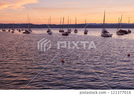 Pier at Sunset with Sailboats, Serene Lake Scene, Orange and Pink Sky, Calm Water, Silhouettes of Boats, Tranquil Evening, Reflections on Water, Peaceful Marina, Dusk Landscape, Nautical Atmosphere Pier at Sunset with Sailboats, Serene Lake Scene, Orange and Pink Sky, Calm Water, Silhouettes of Boats, Tranquil Evening, Reflections on Water, Peaceful Marina, Dusk Landscape, Nautical Atmosphere 121377018