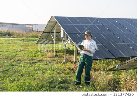 Female farmer with digital tablet on a modern farm using solar panels 121377420