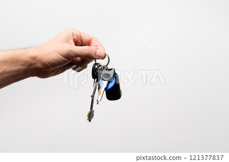 Salesman businessman holding keys, advertising sale, services or purchase of real estate. close-up on gray background 121377837