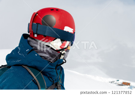 Cheerful and happy man in warm blue jacket, ski mask and helmet looking away, spending extreme weekend in winter season in mountains. Portrait of sporty guy Cheerful and happy man in warm blue jacket, ski mask and helmet looking away, spending extreme weekend in winter season in mountains. Portrait of sporty guy 121377852