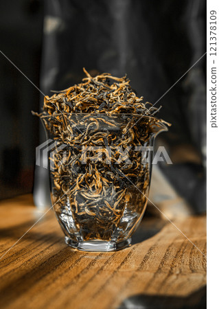 A collection of dried tea leaves elegantly displayed in a beautiful glass container 121378109