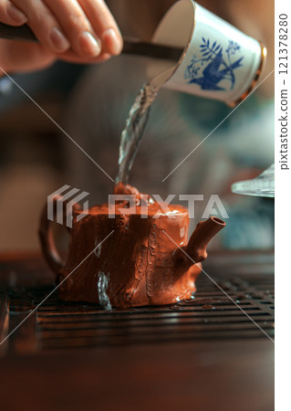 Pouring water carefully into a beautiful, miniature teapot creates a tranquil, cozy moment 121378280