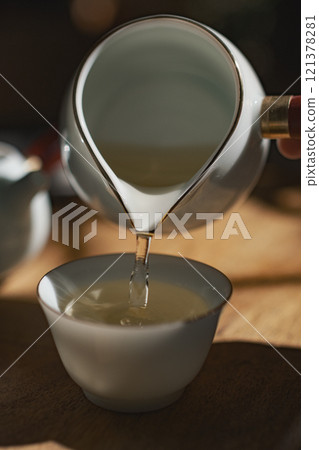 Pouring a comforting cup of tea into a beautiful fine ceramic cup enhances the ritual Pouring a comforting cup of tea into a beautiful fine ceramic cup enhances the ritual 121378281