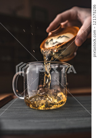 Pouring a Delightful and Aromatic Herbal Tea Into a Beautiful Glass Jug for Enjoyment Pouring a Delightful and Aromatic Herbal Tea Into a Beautiful Glass Jug for Enjoyment 121378286