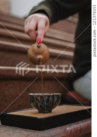 A traditional tea pouring ceremony with a beautiful pot enhances the whole experience 121378355