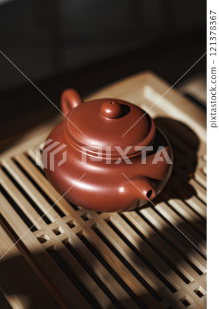 An Elegant Clay Teapot beautifully placed on a stylish Wooden Tea Tray for serving tea 121378367