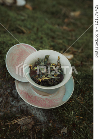 A ceramic bowl filled with vibrant wild greens set against a serene nature backdrop 121378428