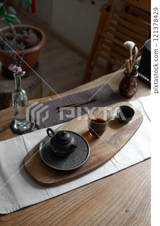 An Elegant Tea Setup Positioned on a Wooden Table Surrounded by Natural Elements and Beauty 121378429