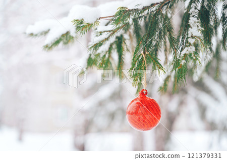 Red glasses bauble on christmas tree with snow outdoor 121379331