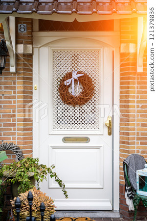 Facade of typical Dutch door house with brick walls, steps, front door windows. Doors on the street, Netherlands 121379836