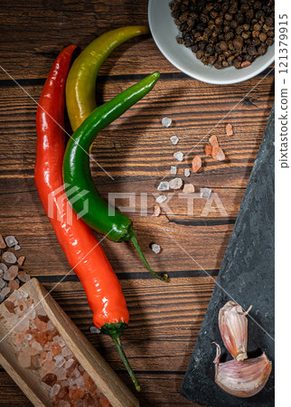 rustic cutting board with rosemary, pepper and spices , dark rustic wooden background, top view, place for text rustic cutting board with rosemary, pepper and spices , dark rustic wooden background, top view, place for text 121379915