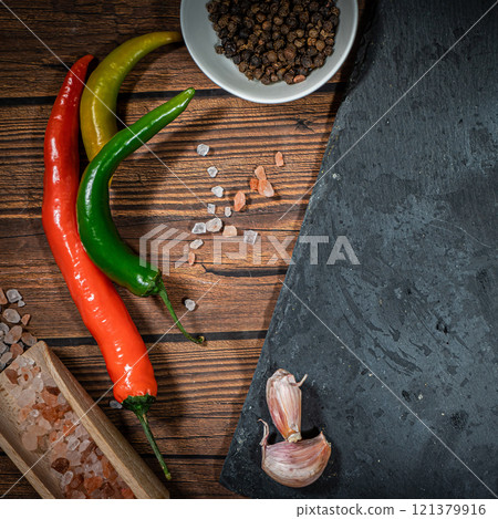 rustic cutting board with rosemary, pepper and spices , dark rustic wooden background, top view, place for text rustic cutting board with rosemary, pepper and spices , dark rustic wooden background, top view, place for text 121379916
