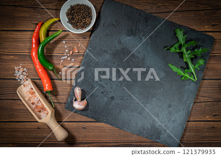 rustic cutting board with rosemary and spices , dark rustic wooden background, top view, place for text rustic cutting board with rosemary and spices , dark rustic wooden background, top view, place for text 121379935