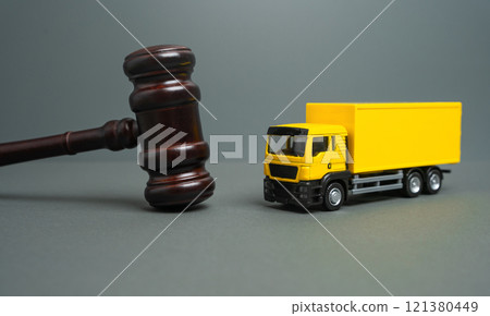 Yellow truck and judge's gavel. Court case. New laws and acts. Restrictions and regulations. Bankruptcy. Sale of assets of a transport company through auction. 121380449