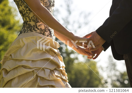 Closeup of bride and groom facing each other holding hands 121381064