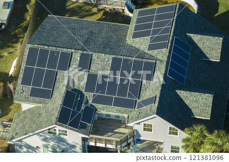 Aerial view of american home roof with blue solar photovoltaic panels for producing clean ecological electric energy. Investing in renewable electricity for retirement income Aerial view of american home roof with blue solar photovoltaic panels for producing clean ecological electric energy. Investing in renewable electricity for retirement income 121381096