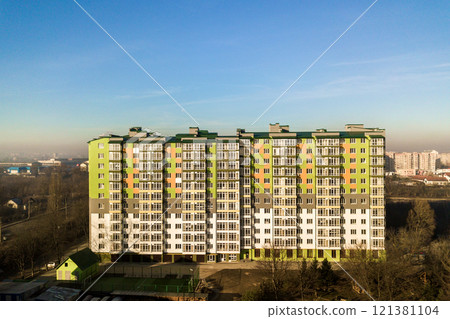 Aerial view of a tall residential apartment building with many windows and balconies. Aerial view of a tall residential apartment building with many windows and balconies. 121381104