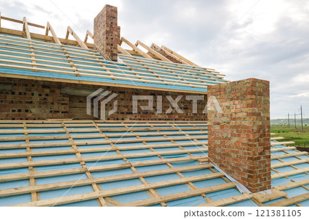 Aerial view of a brick house with wooden roof frame under construction. Aerial view of a brick house with wooden roof frame under construction. 121381105