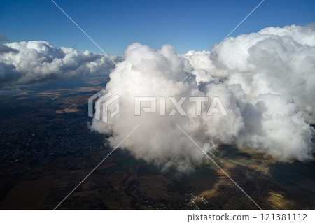 Aerial view from airplane window at high altitude of earth covered with white puffy cumulus clouds Aerial view from airplane window at high altitude of earth covered with white puffy cumulus clouds 121381112