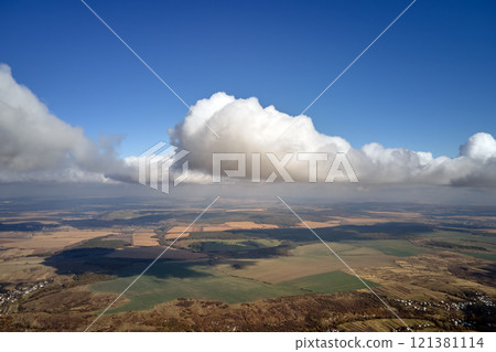 Aerial view from airplane window at high altitude of earth covered with white puffy cumulus clouds Aerial view from airplane window at high altitude of earth covered with white puffy cumulus clouds 121381114
