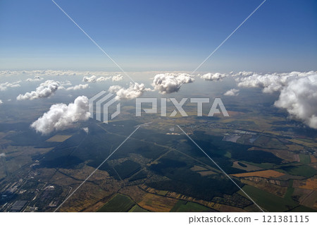 Aerial view from airplane window at high altitude of earth covered with puffy cumulus clouds forming before rainstorm. Aerial view from airplane window at high altitude of earth covered with puffy cumulus clouds forming before rainstorm. 121381115