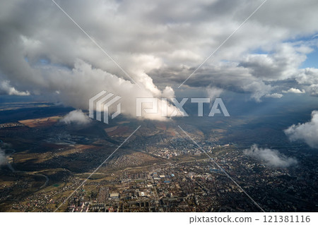 Aerial view from airplane window at high altitude of distant city covered with puffy cumulus clouds forming before rainstorm Aerial view from airplane window at high altitude of distant city covered with puffy cumulus clouds forming before rainstorm 121381116