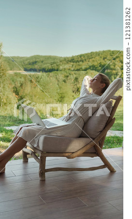 Young woman freelancer sitting on a wooden chair relaxing after work Young woman freelancer sitting on a wooden chair relaxing after work 121381262