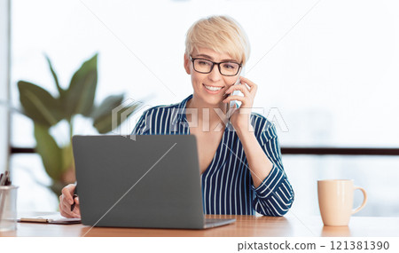 Business Communication. Woman Talking On Mobile Phone Using Laptop Working In Modern Office. Selective Focus Business Communication. Woman Talking On Mobile Phone Using Laptop Working In Modern Office. Selective Focus 121381390