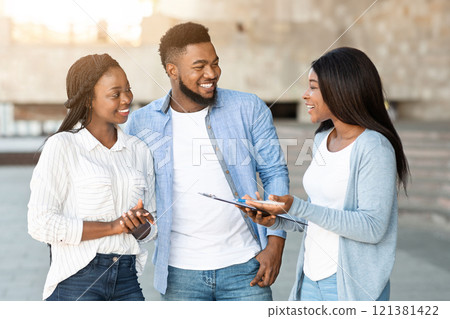 Social survey concept. Smiling woman filling questionnaire with young african american couple, holding pen and clipboard Social survey concept. Smiling woman filling questionnaire with young african american couple, holding pen and clipboard 121381422