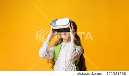 Little Schoolgirl In VR Glasses Experiencing Virtual Reality During Innovative School Lesson On Yellow Studio Background. Panorama Little Schoolgirl In VR Glasses Experiencing Virtual Reality During Innovative School Lesson On Yellow Studio Background. Panorama 121381568