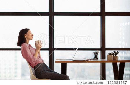 Cup Of Tea And Chill. Woman sitting at desk, drinking hot coffee during her break at work and enjoying morning, dreaming 121381587