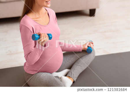 Active Pregnancy. Closeup of pregnant woman lifting dumbbells at home. Free space, selective focus 121381684
