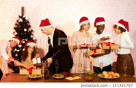 Christmas Party. Joyful Multiracial Friends Exchanging Xmas Gifts Giving Presents Boxes Congratulating Each Other Indoors 121381707