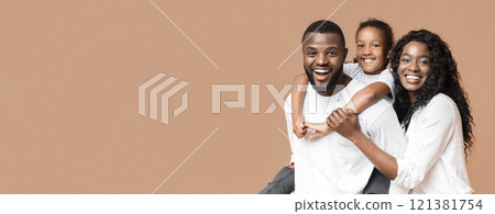 Family fun. Young african american parents spending time with their little daughter, laughing together over yellow background Family fun. Young african american parents spending time with their little daughter, laughing together over yellow background 121381754