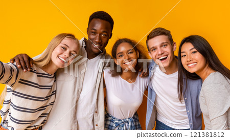 Friendly international students embracing and taking selfie over yellow background Friendly international students embracing and taking selfie over yellow background 121381812
