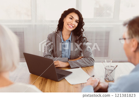 Ready To Help. Smiling hispanic saleswoman listening to senior couple who asking her about financial advice 121381823